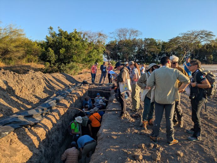 people surrounding, and standing inside, a paleoseismological trench