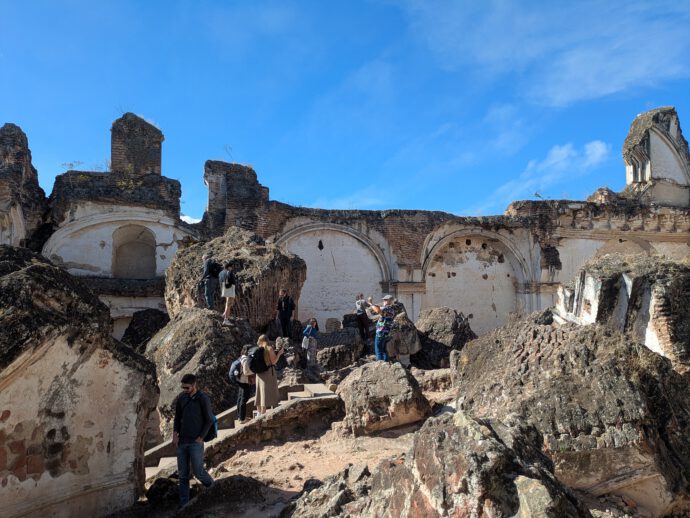 people walking around the ruins of a church