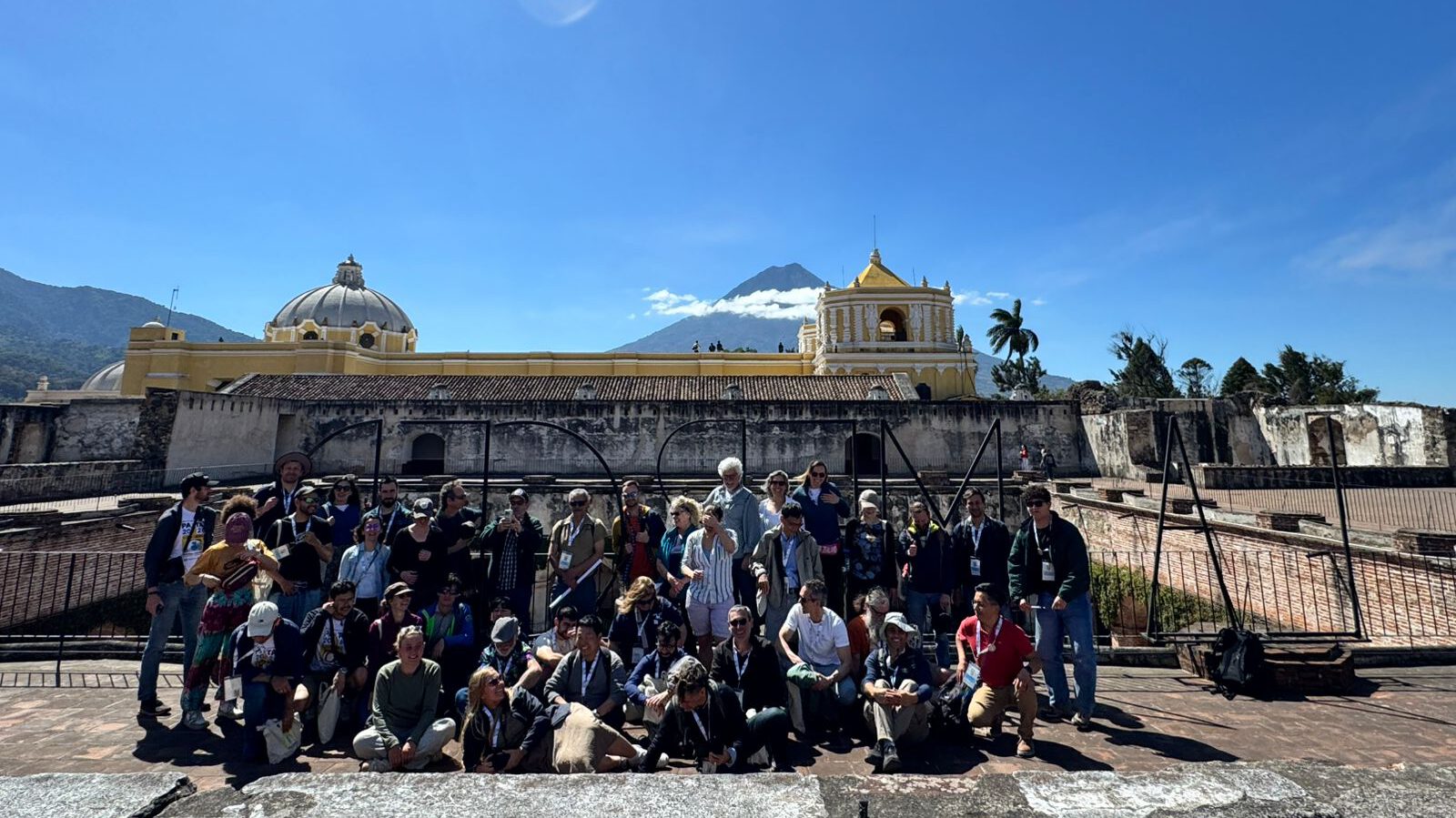 group photo on a church's roof, volcano in the background